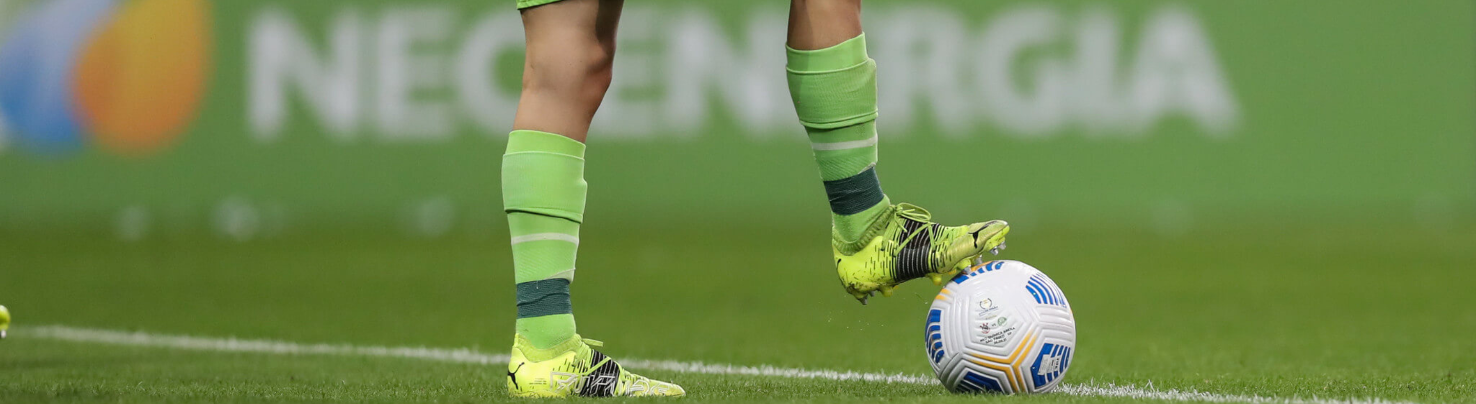 Imagem cortada de pernas de jogadora de futebol com bola no pé